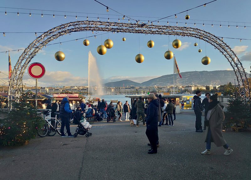 Eingang des Weihnachtsmarktes in Genf Weihnachten am Quai mit beleuchtetem Torbogen, Dekorationen und Jet d’Eau im Hintergrund