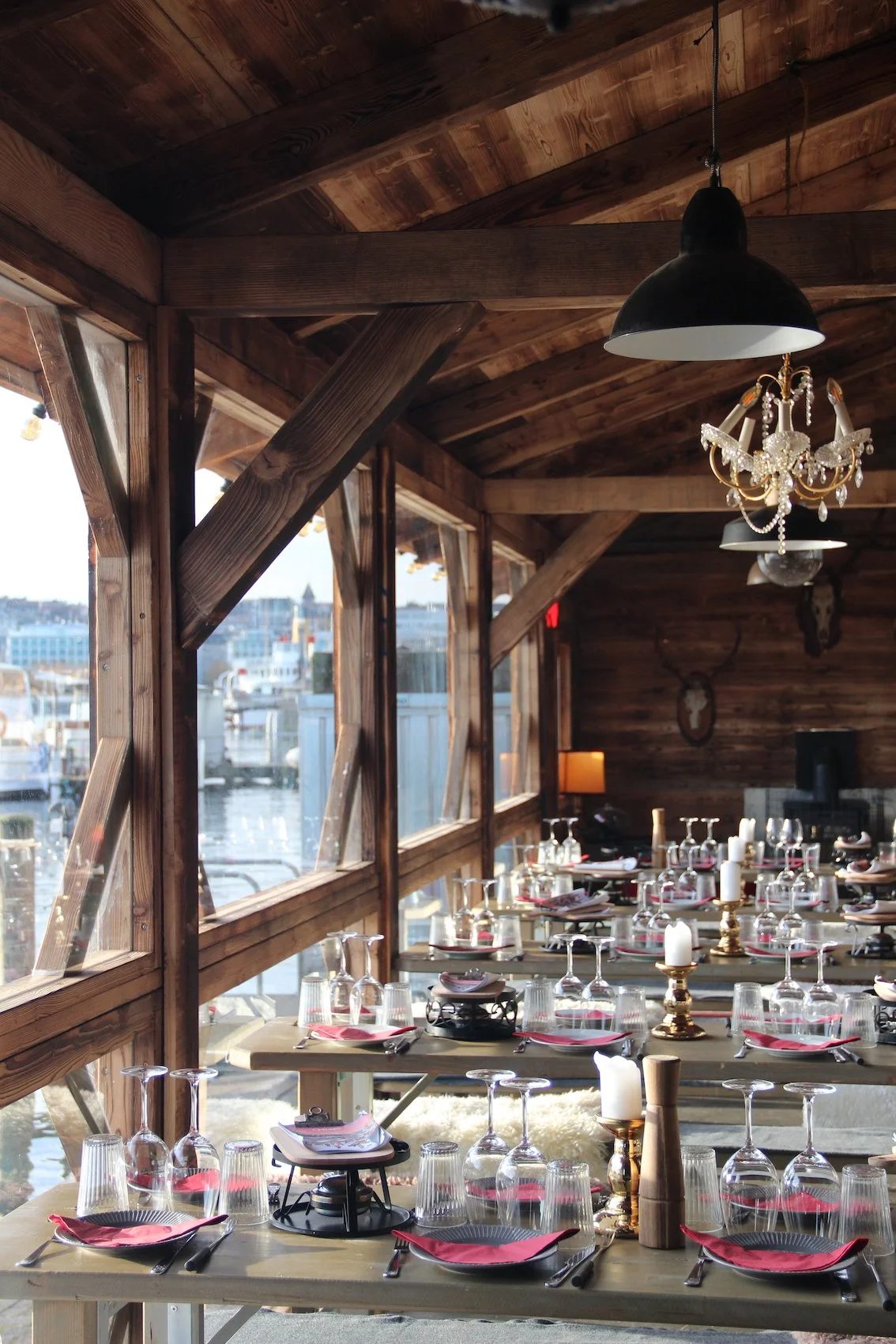 Innenraum des Fondue-Chalets Noël au Quai mit großen Tischen am Seeufer gedeckt