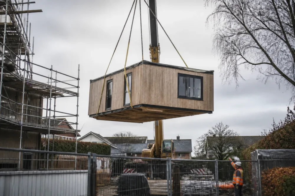 Module de maison modulaire soulevé par une grue sur un chantier réel, illustrant la rapidité de pose