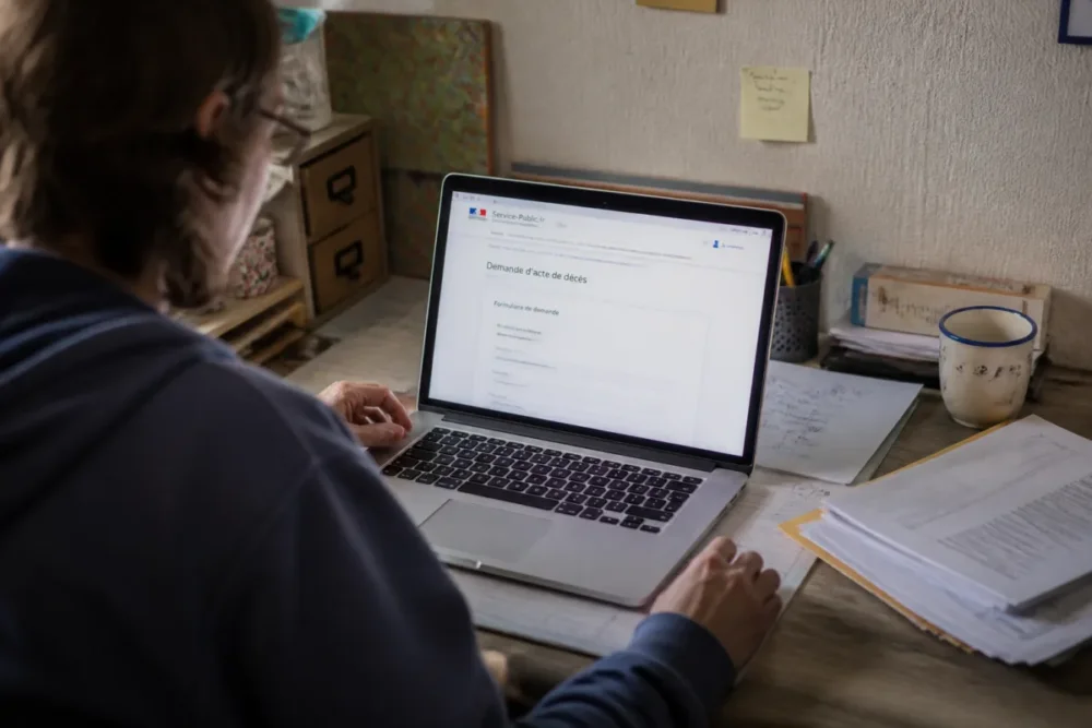 Personne remplissant une demande d'acte de décès en ligne sur un ordinateur