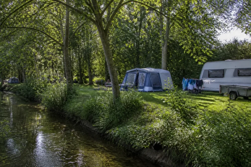Vue réaliste d’un camping familial en bord de rivière dans l’Ain
