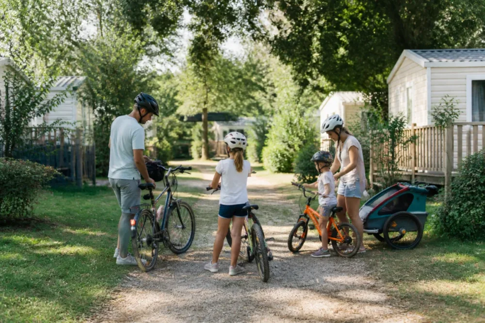 Famille à vélo dans un camping familial verdoyant près de Pont-de-Vaux