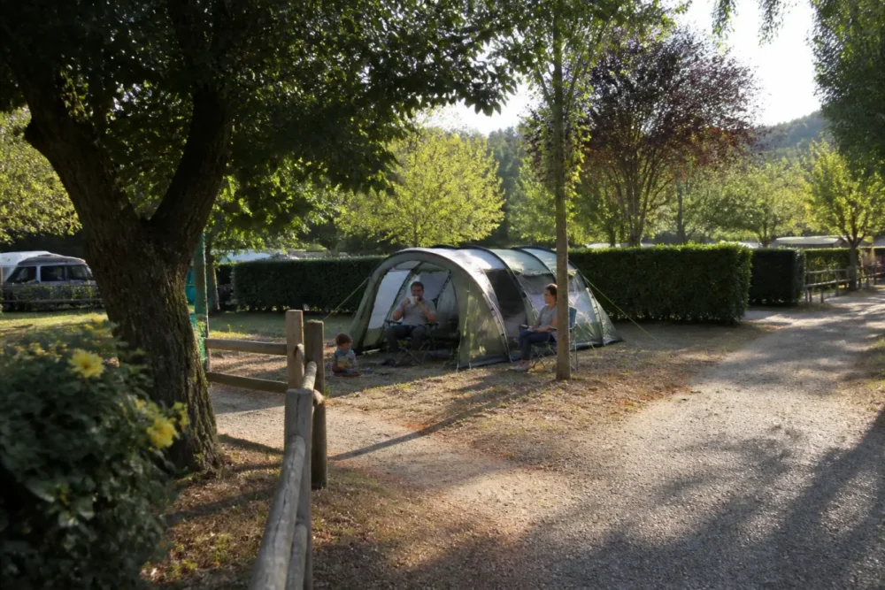 Photo réaliste d’un emplacement de camping ensoleillé le matin avec une zone ventilée pour une famille avec enfants