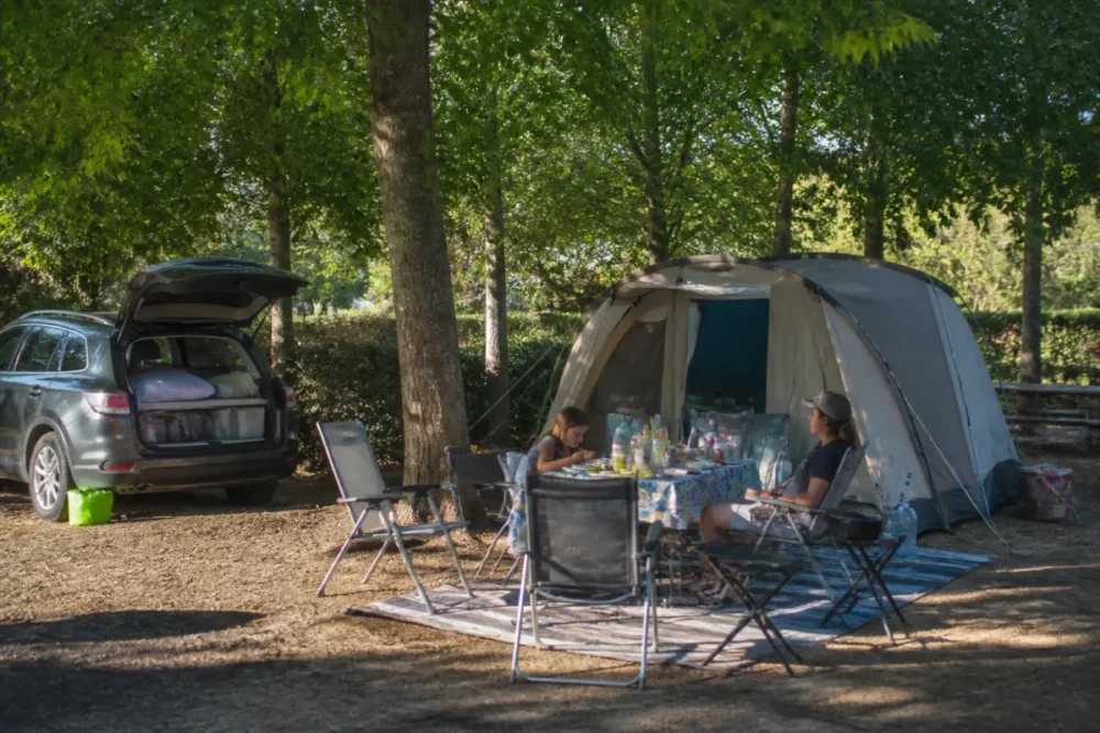 Emplacement de camping ombragé pour une famille en France avec tente et table de repas