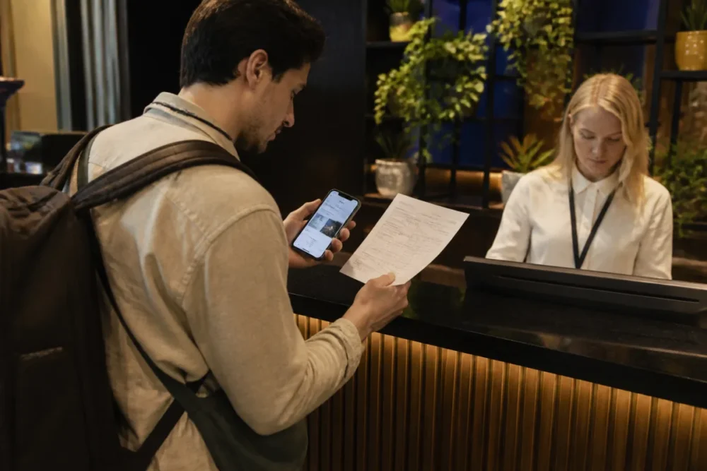 Voyageur vérifiant une facture d’hôtel à la réception pour éviter les frais cachés hôtel
