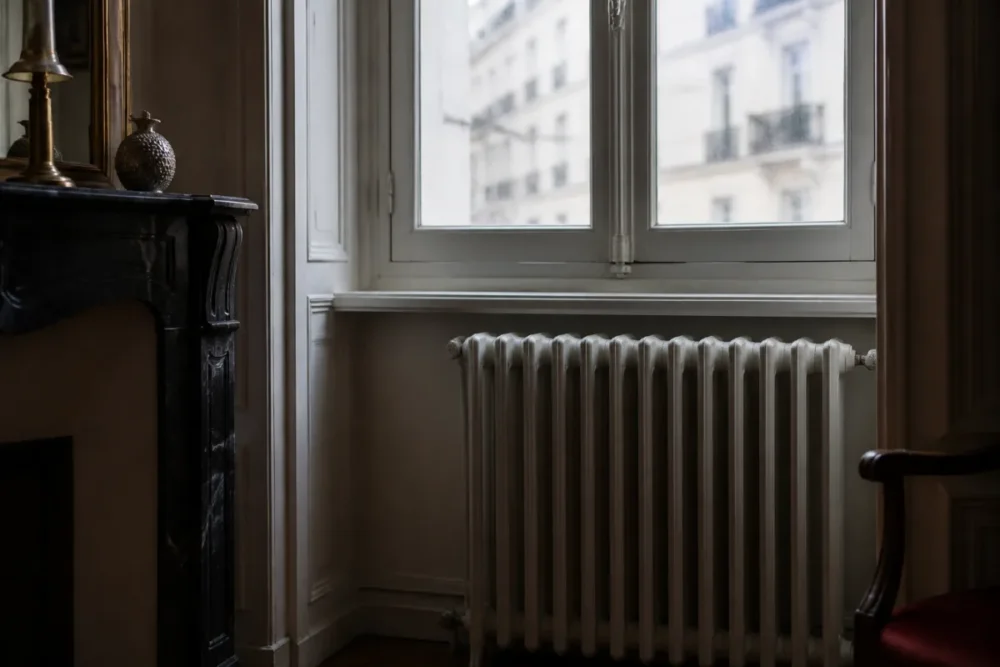 Fenêtre ancienne avec courant d’air près d’un radiateur dans une maison énergivore