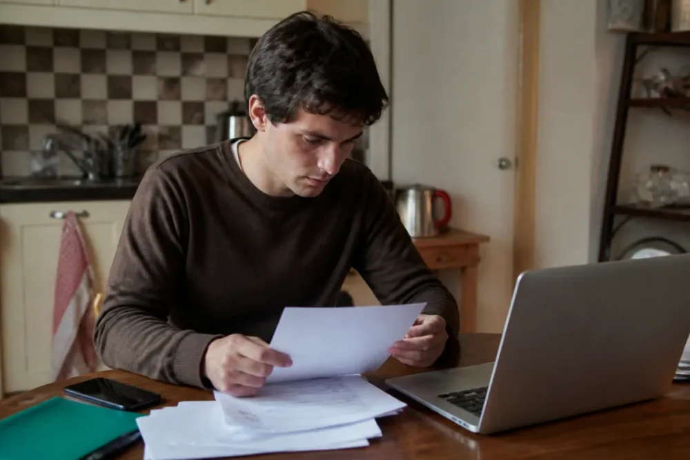 Photo réaliste d’une personne hébergée préparant un dossier de justificatif de domicile avec des documents administratifs
