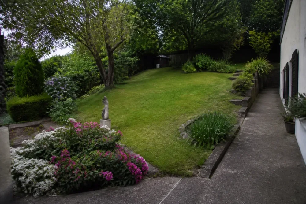 Jardin en pente avec obstacles montrant pourquoi le prix de tonte de pelouse varie