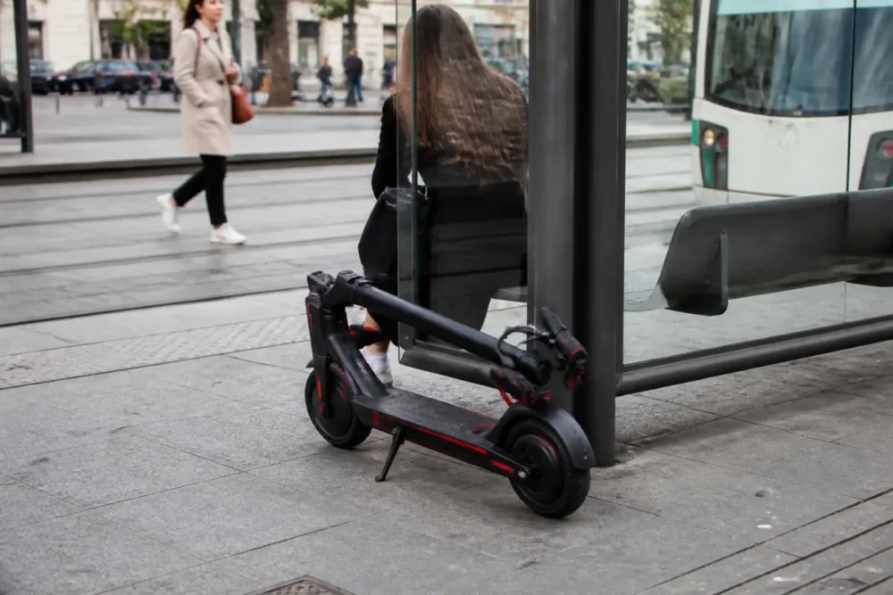 Trottinette électrique pliée près d’un tramway pour un trajet urbain multimodal