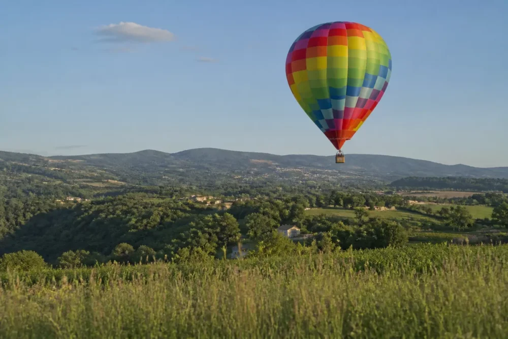 Photo réaliste d’une montgolfière au-dessus des paysages de l’Ardèche près d’Annonay