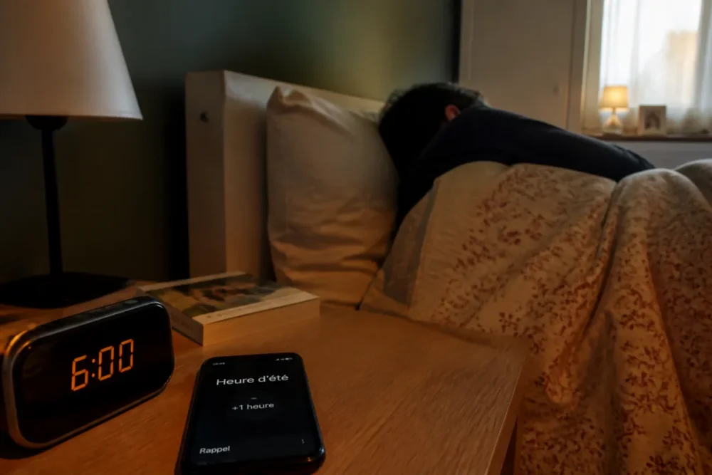 Réveil, smartphone et chambre pour illustrer les effets du changement d'heure 2026