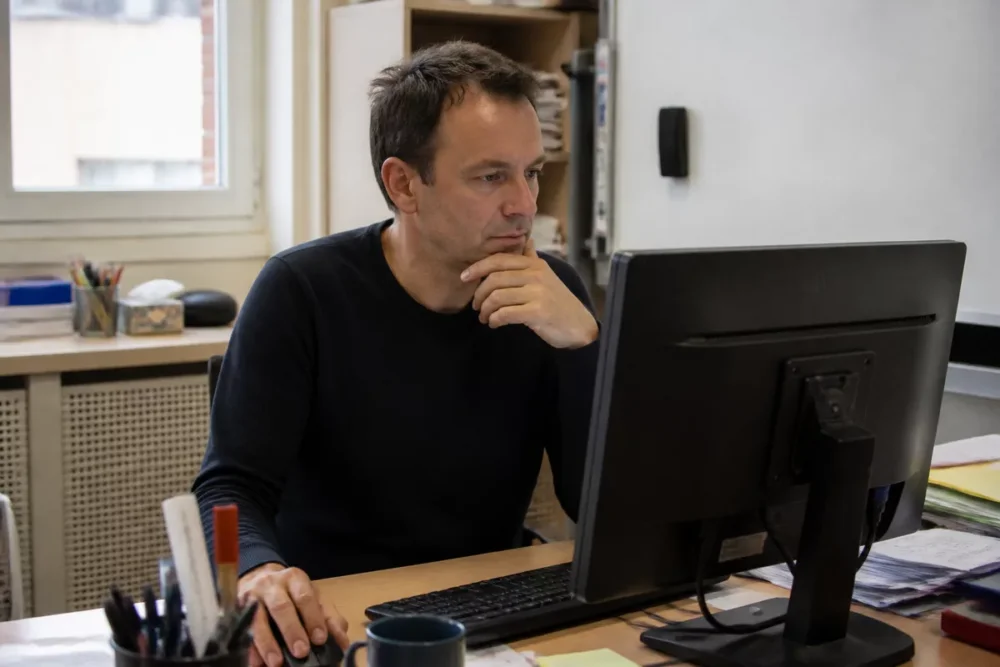 Photo réaliste d’un enseignant vérifiant iProf Bordeaux sur son ordinateur
