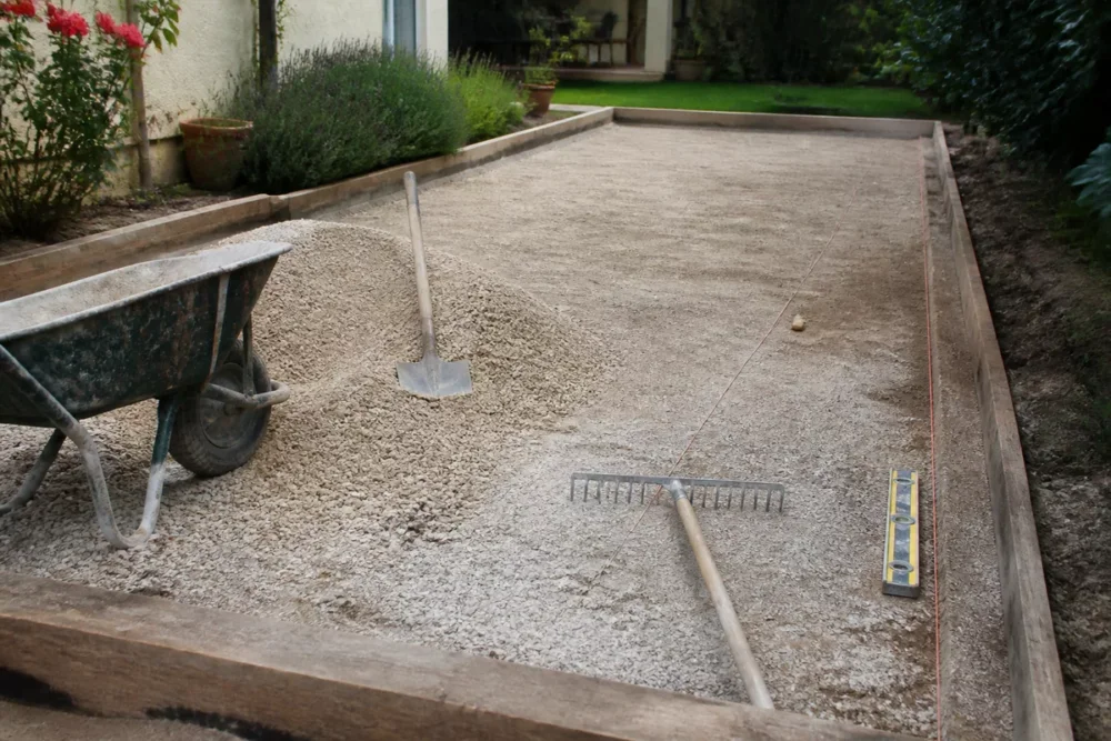 Chantier réel d’aménagement d’un terrain de pétanque dans un jardin.