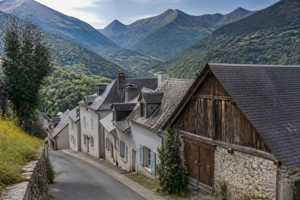 Rue de Campan avec maisons pyrénéennes et montagnes en arrière-plan